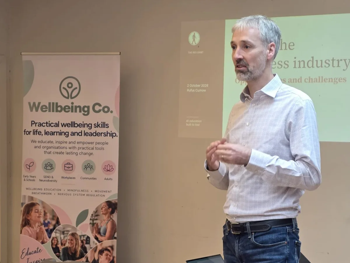 Rufus Curnow presenting AI for the wellness industry beside a Wellbeing Co. banner